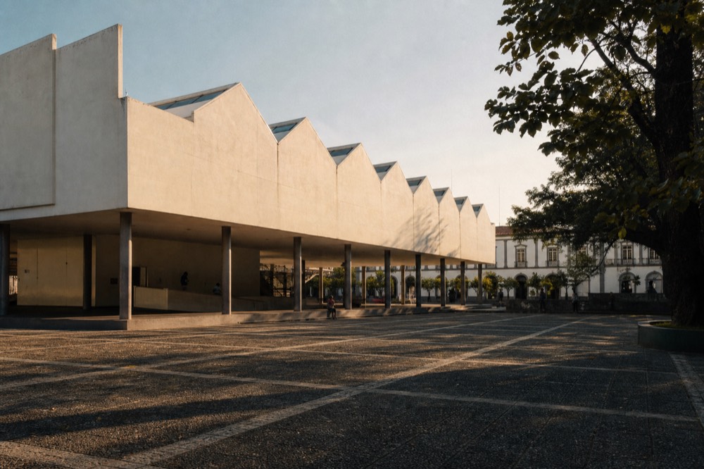 A pale travertine museum building with a sawtooth skylit roof against a clear sky